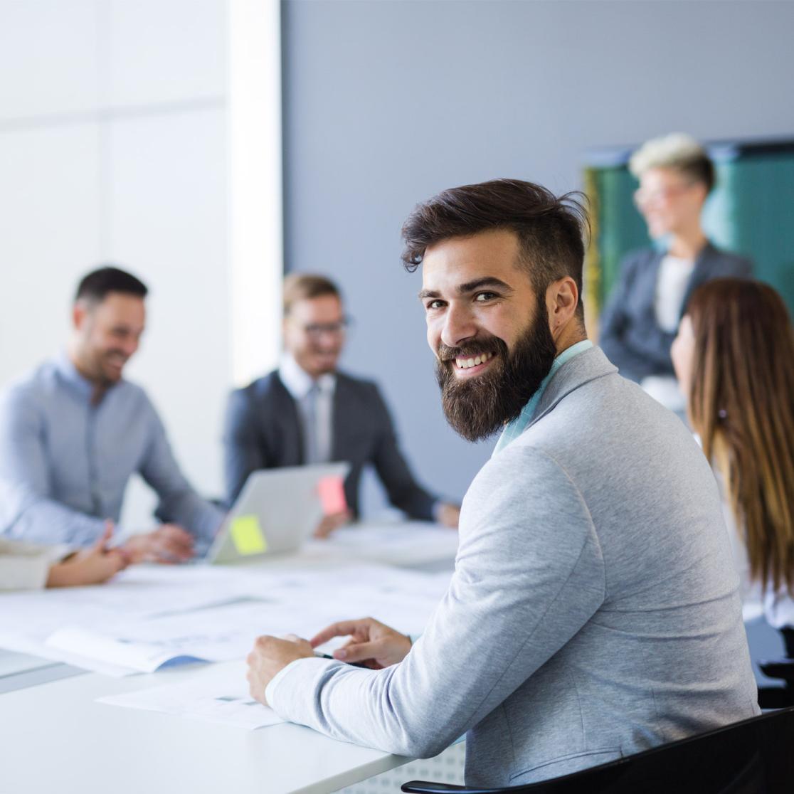 Businesspartners working around a table with one member smiling into the camera